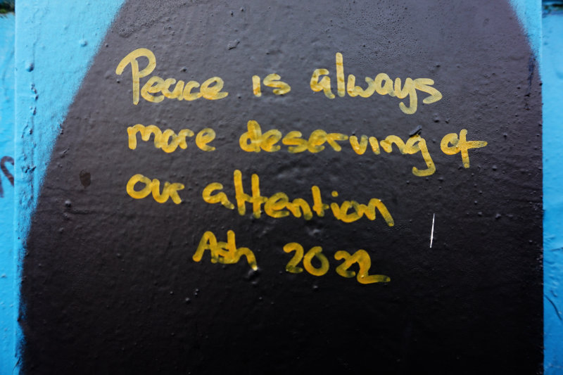 Ash's sign at the peace wall, Belfast, Northern Ireland. It says "peace is always more deserving of our attention"
