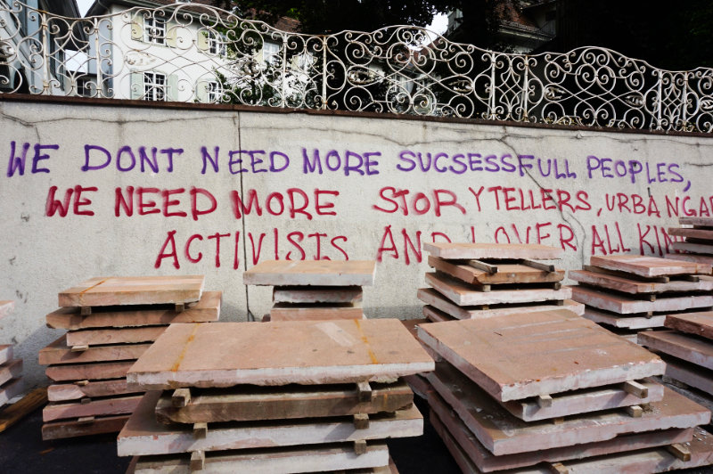 Graffiti in Basel, Switzerland. Says "We don't need more successful peoples, we need more storytellers, urban gardeners, activists and lover all kinds" (sic)