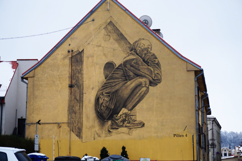 Street art in Kaunas, Lithuania. A woman sitting on a bird house.