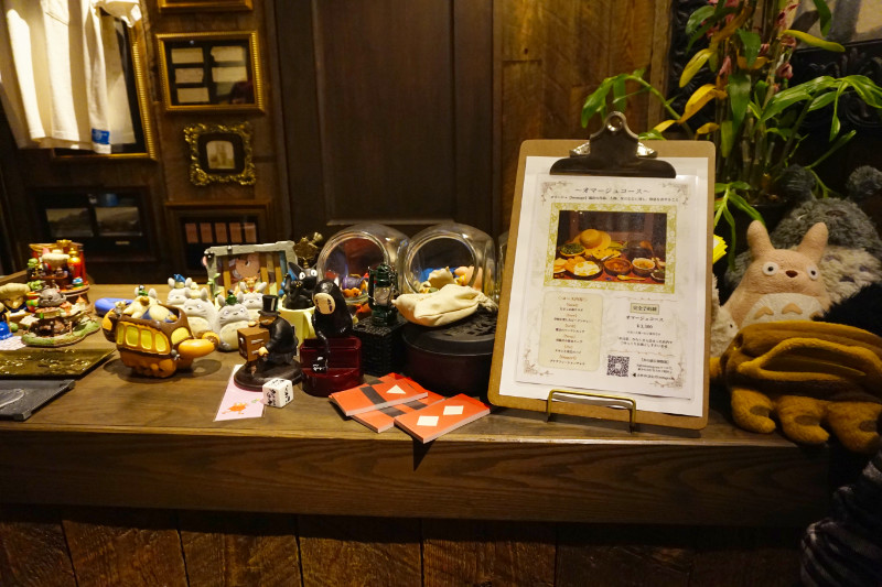 Countertop in Corn Barley restaurant, Tokyo, Japan. There is a menu with the Ghibli set menu, and lots of trinkets like No-Face and Catbus.