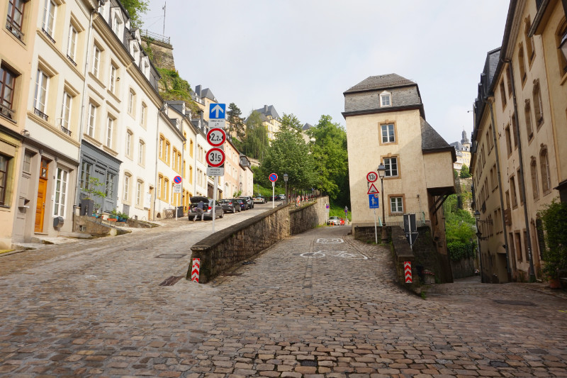 The Grund, Luxembourg. Looking at 3 streets, the left going sharply uphill, the middle going mildly uphill, and the other is a narrow street going down towards the river.