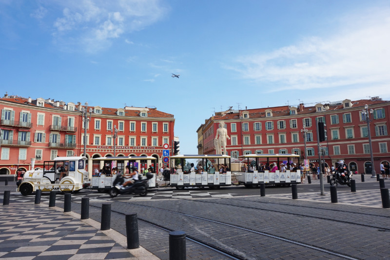 Place Massena, Nice, France. There's a tourist train trundling in front of the statue of Apollo, and a huge plane flying overhead