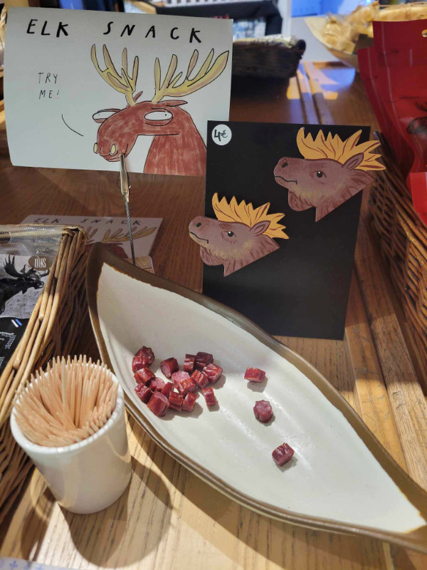 Samples of elk meat, Tallinn, Estonia. There's a postcard in the background with a ridiculous drawing of an elk saying "TRY ME!"