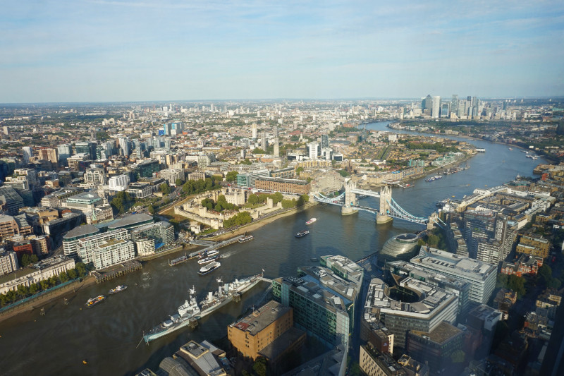 View from The Shard, London. HMS Belfast, Tower Of London and Tower Bridge in the foreground with the Thames flowing round to the left and then back right to the skyscrapers of Canary Wharf