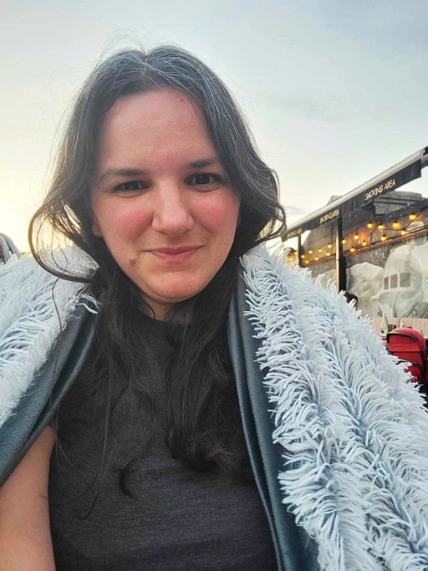 Me at the Linea / Closer To The Moon bar, Bucharest, Romania. I have a fluffy blanket over my shoulders.