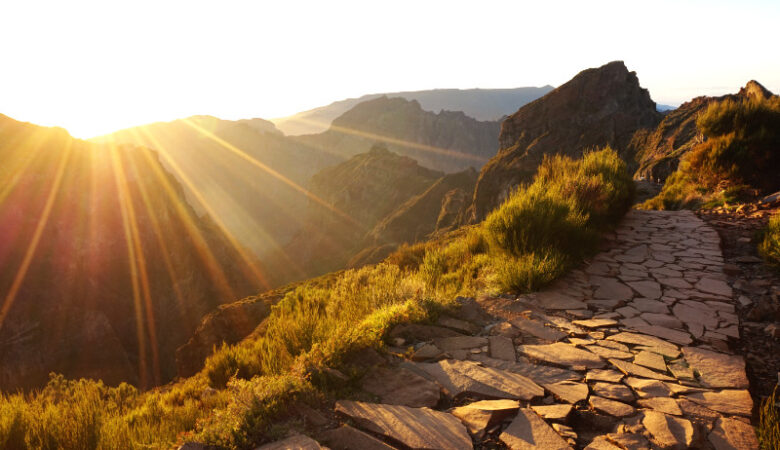 Pico do Areeiro sunset, Madeira, Portugal. View along a brick path on the right towards some mountains, and on the left the sun setting over the mountain peaks.