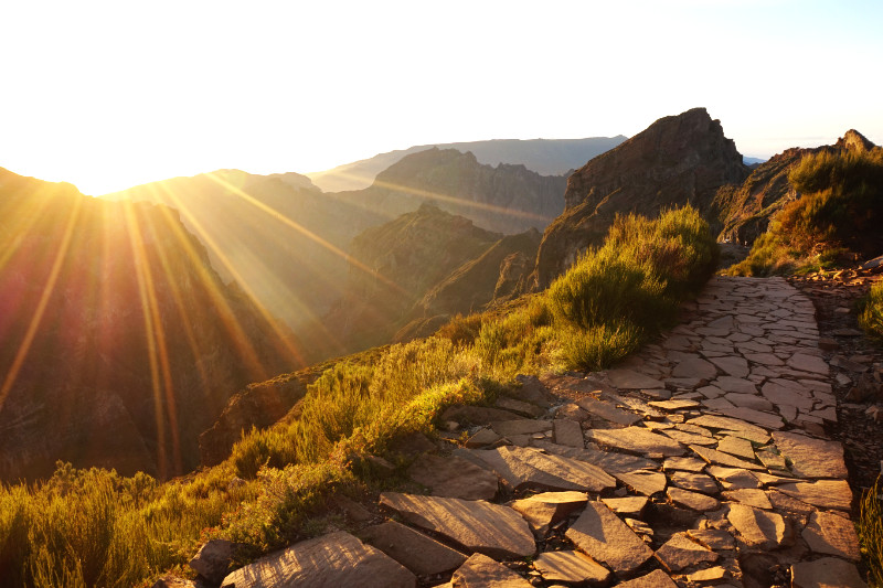 Pico do Areeiro sunset, Madeira, Portugal. View along a brick path on the right towards some mountains, and on the left the sun setting over the mountain peaks.