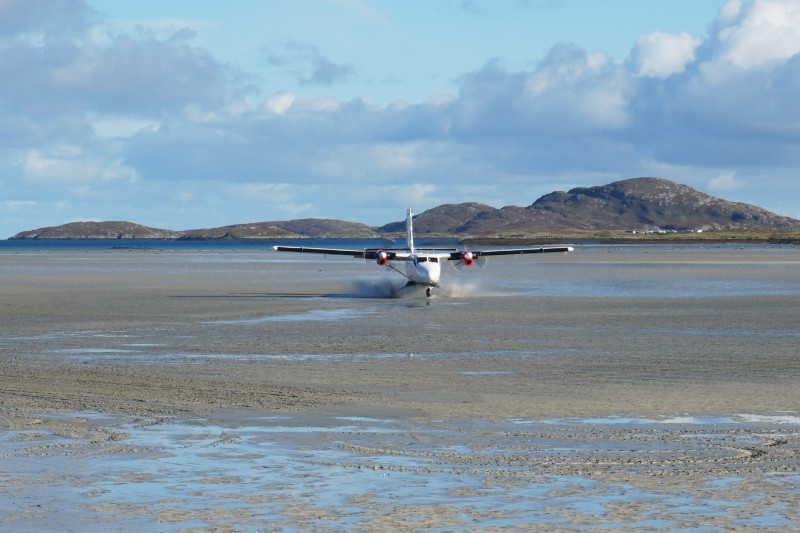 Twin Otter Loganair plane landing on the beach in Barra, Scotland