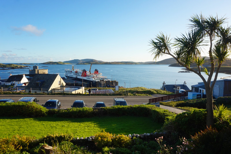 Castlebay, Barra, Scotland. Overlooking Kisimul Bay with the ferry docked at the port. On the right hand side is a kind of palm tree.